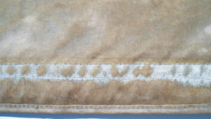 The woven texture of the underlying fabric eventually appears when outer coatings deteriorate, as seen in this close up of a 27 month old flybridge seat cover. The boat, used in boat shows, spent time in ports along the west coast, from San Francisco Bay to San Diego Harbor.