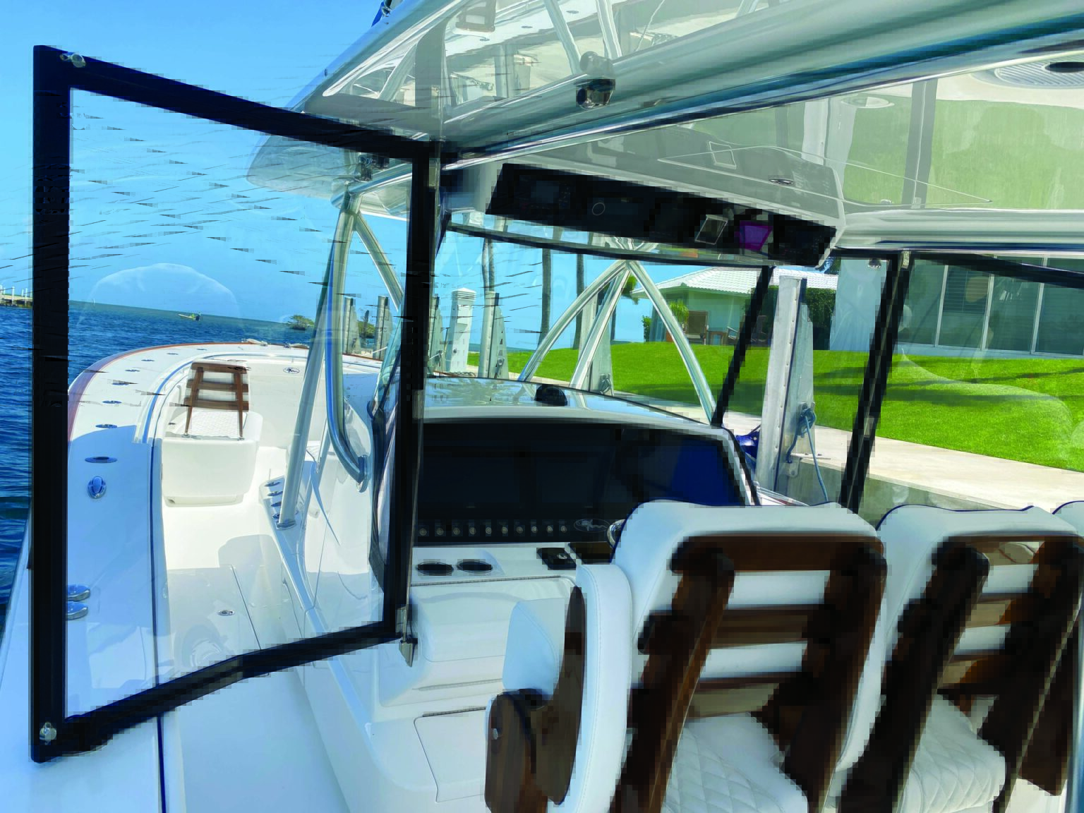 Custom black-framed clear enclosure wing door open beside a center-console helm, leaving access around the console