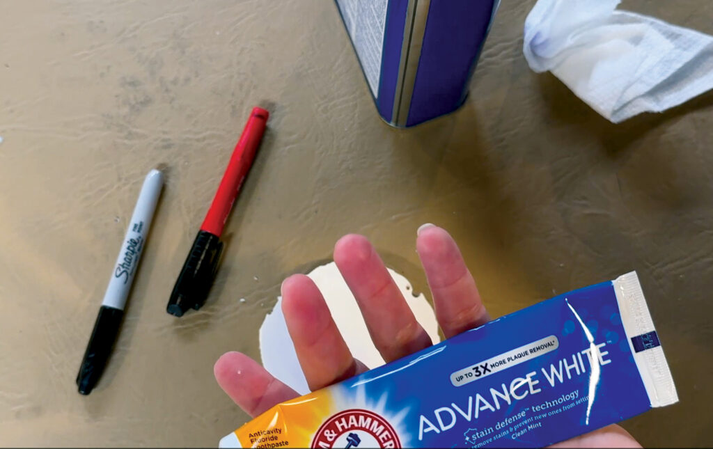 Keri Ames's hand holding Arm & Hammer toothpaste.