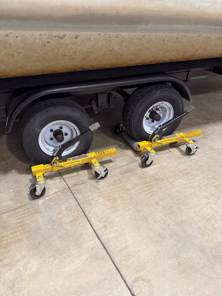 The Daytona wheeled dolly underneath two wheels of a boat trailer.