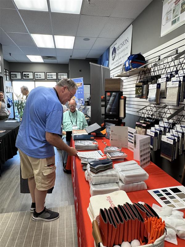 A fabricator reviews supplier materials at a booth.