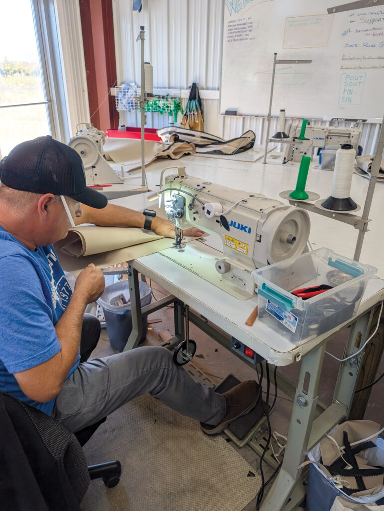 Marine upholstery workshop with a person stitching heavy-duty fabric using an industrial Juki sewing machine.