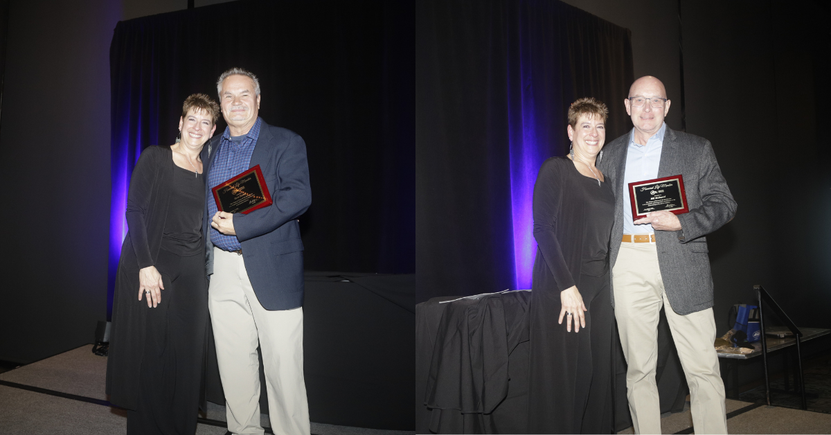 Two recipients holding plaques stand beside each other, smiling. The backdrop is dark with purple lighting, enhancing the celebratory mood.