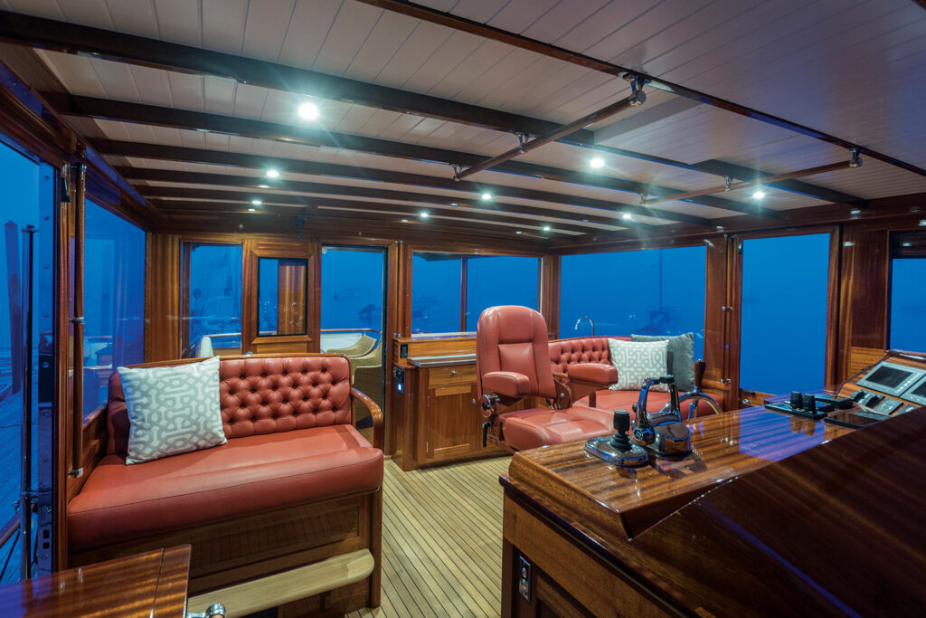 Boat interior featuring red leather seating, polished wood accents and large windows.