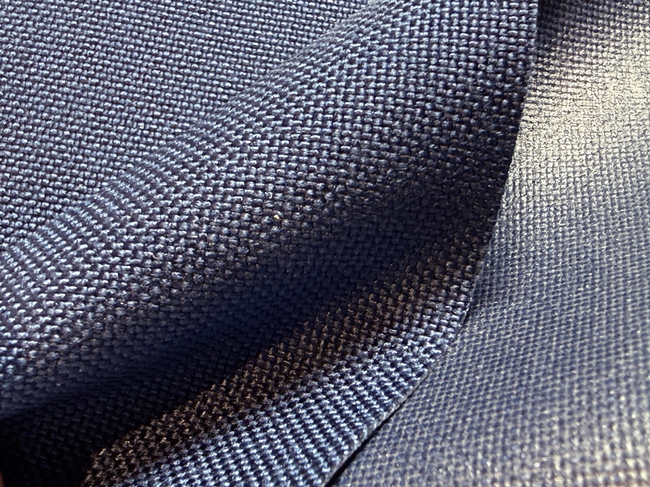 Navy blue textured nylon fabric draped, showcasing its weave and color depth.