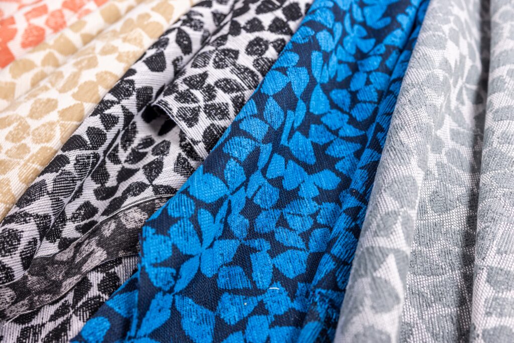 A collection of textured fabrics in various colors, featuring leaf-like patterns in shades of blue, black, gray, white and beige.