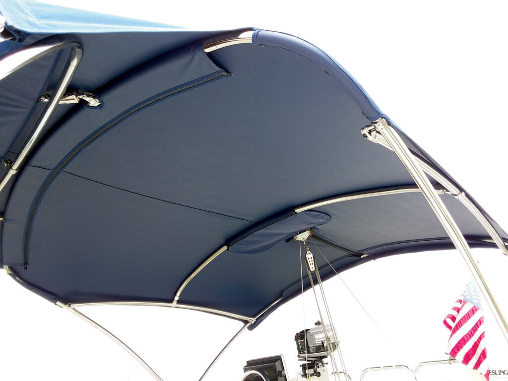 Navy blue boat canopy viewed from underneath, showcasing metallic supports and an American flag in the background.