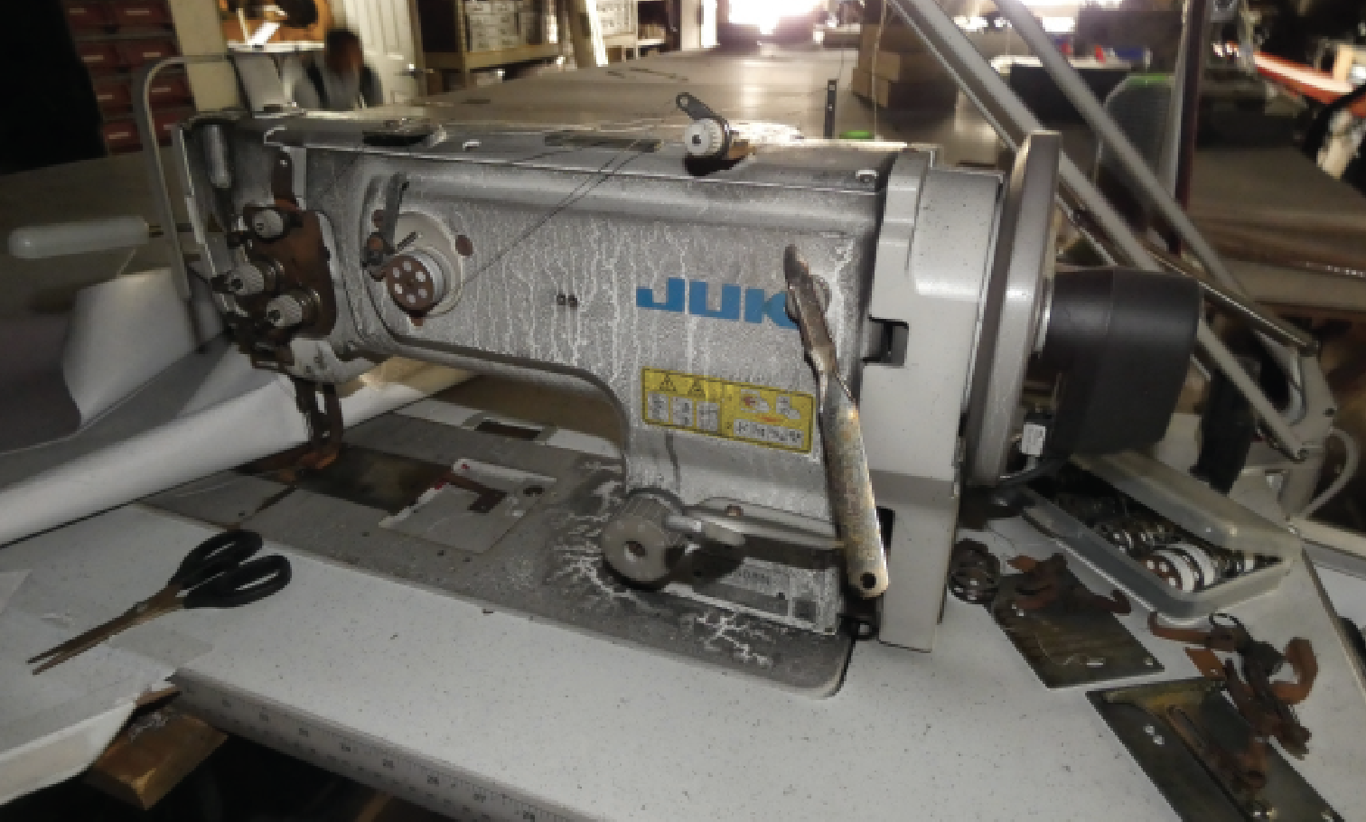JUKI sewing machine on a work table with scissors and various tools.