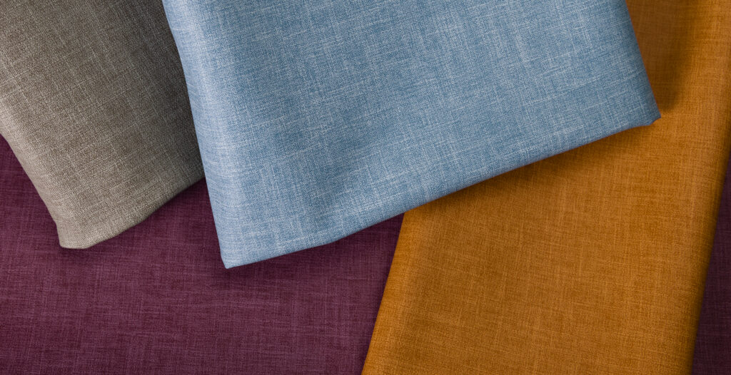Textiles in shades of brown, light blue, orange and deep purple arranged in overlapping layers, showcasing varied textures.