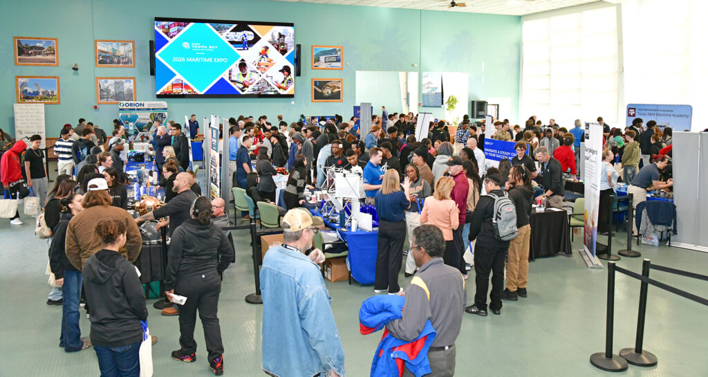 Crowded expo hall featuring diverse attendees engaged at booths with marine industry displays and presentations in a vibrant setting.