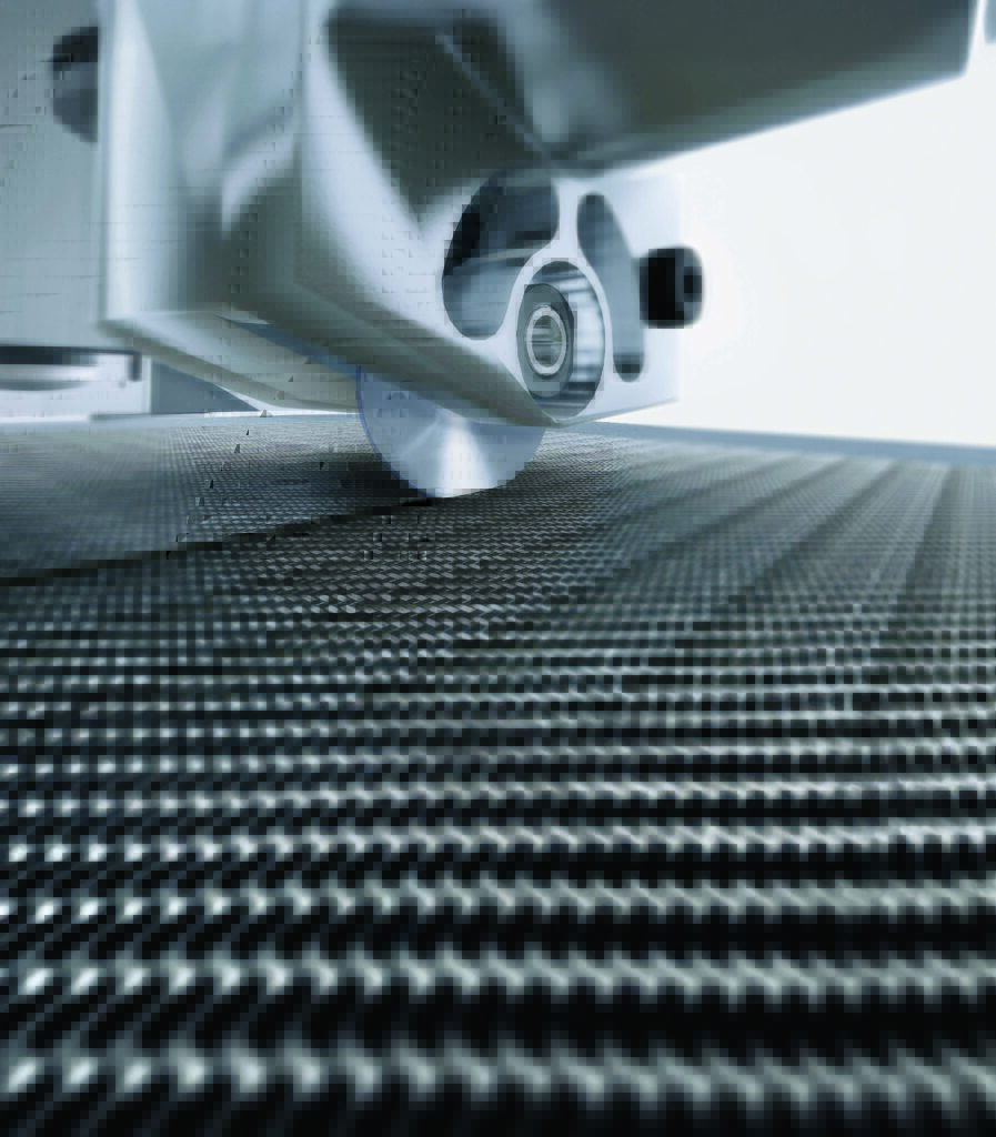 Close-up of a cutting tool on a smooth, textured carbon fiber surface.